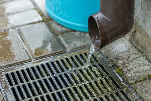 Принти на полотні Water flows from a brown gutter into a metal drain grate, creating a small stream