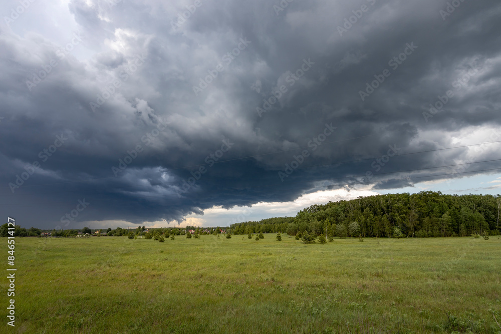 A vast, dark, and dramatic sky hangs low over a lush green meadow. The ominous clouds suggest an impending storm, while the fresh green grass and trees symbolize the vibrancy of spring. A vast, dark, and dramatic sky hangs low over a lush green meadow. The ominous clouds suggest an impending storm, while the fresh green grass and trees symbolize the vibrancy of spring.