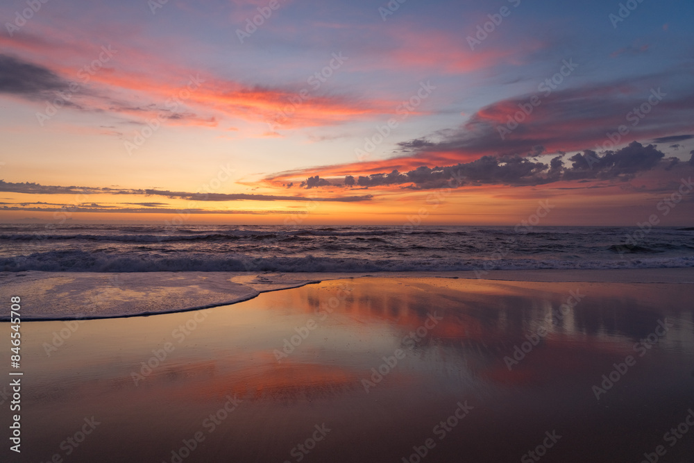 Sunset landscape of a beautiful and paradisaical beach with the clouds reflected on the water. Summer and vacations concept background. Sunset landscape of a beautiful and paradisaical beach with the clouds reflected on the water. Summer and vacations concept background.