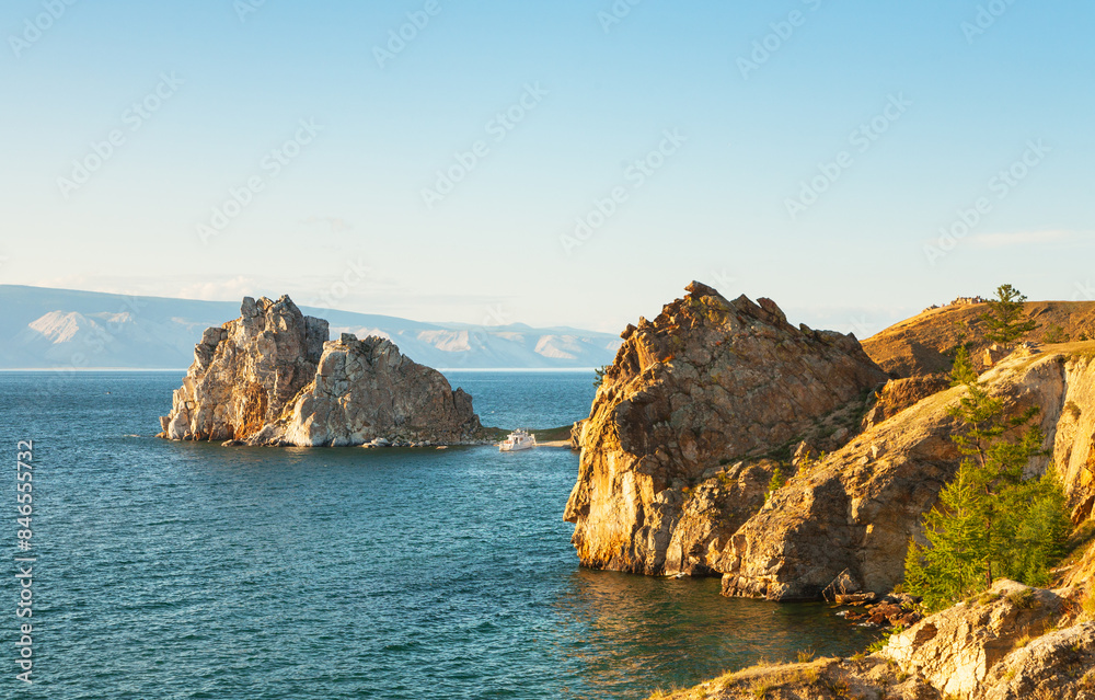 Baikal Lake on sunny summer day. Beautiful landscape of coast of Olkhon Island. View of famous Shamanka Rock - natural landmark of island. Natural background. Summer travel and outdoor recreation Baikal Lake on sunny summer day. Beautiful landscape of coast of Olkhon Island. View of famous Shamanka Rock - natural landmark of island. Natural background. Summer travel and outdoor recreation