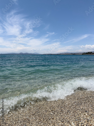 Fototapeta Naklejka Na Ścianę i Meble -  waves of  sea on pebble beach under blue sky in sunny summer day