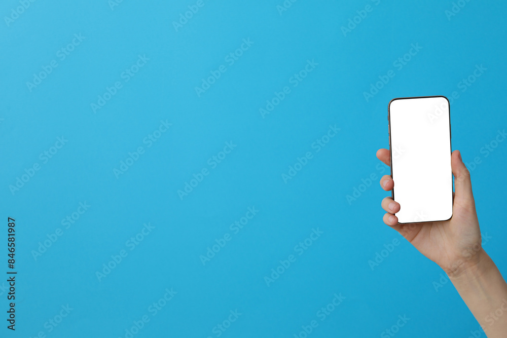 Female hand holding a smartphone on a blue background Female hand holding a smartphone on a blue background
