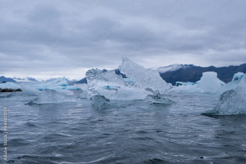 Jökulsárlón glacial lagoon. Sightseeing in Iceland in autumn, glacial icebergs in a lagoon with cloudy skies and mountains in the background. Jökulsárlón glacial lagoon. Sightseeing in Iceland in autumn, glacial icebergs in a lagoon with cloudy skies and mountains in the background.