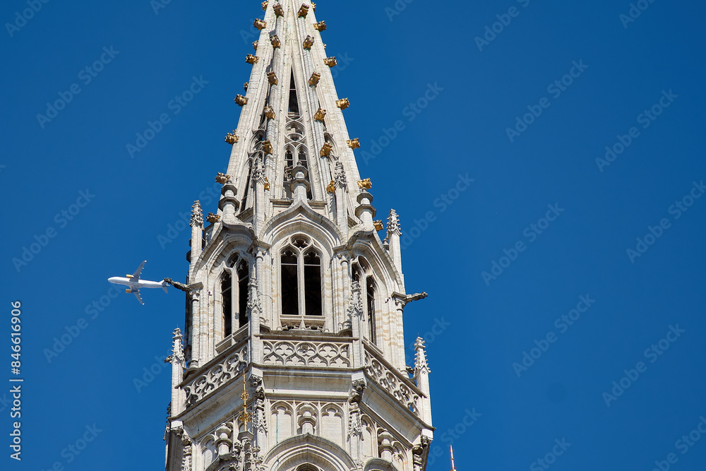 A plane passing by the Brussels City Hall Tower on the Grand Place A plane passing by the Brussels City Hall Tower on the Grand Place