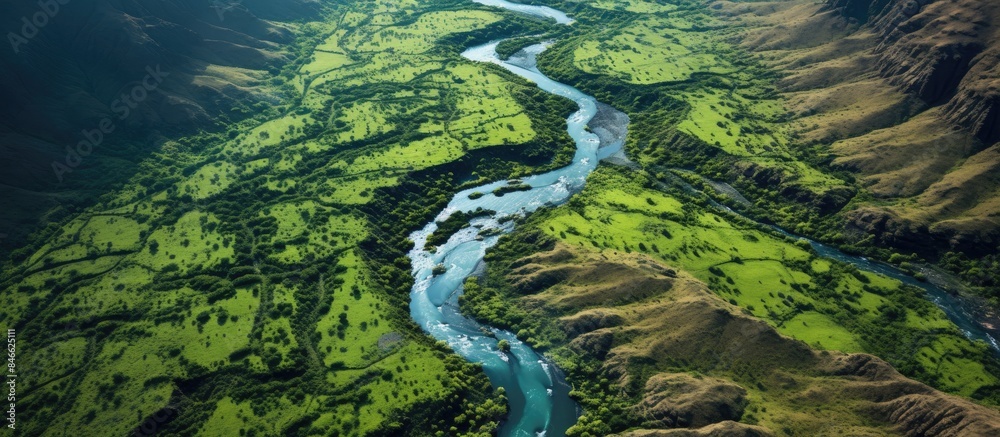 Obraz premium Scenic aerial shot of a verdant canyon with a meandering river, perfect for eco-friendly trips, Earth Day, and outdoor adventures, with copy space image.