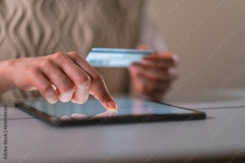 クレジットカードを持ってインターネットショッピングをする女性の手元のクローズアップ クレジットカードを持ってインターネットショッピングをする女性の手元のクローズアップ
