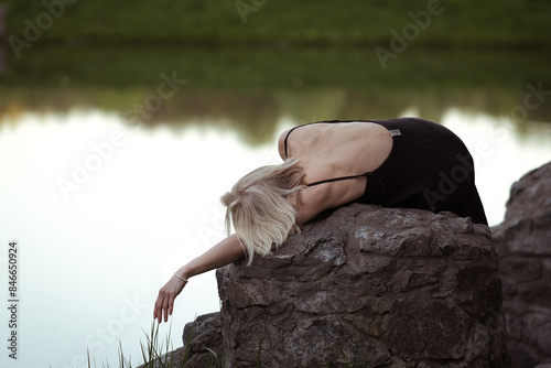 A woman is lying on a stone near the lake at wam summer evening photo