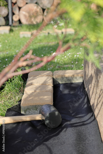 Laying an anti-weed mat in the garden together with paving stones and decorative pebbles.