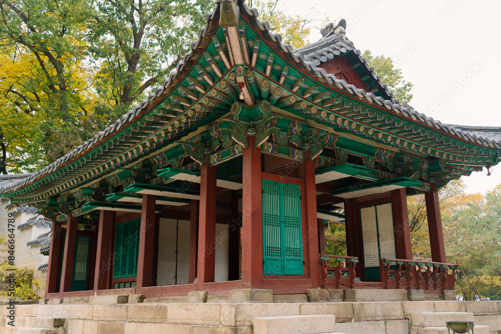 a traditional Korean pavilion with a tiled roof and green window details, set amidst lush trees in Changdeokgung Palace’s Biwon Garden, Seoul. a traditional Korean pavilion with a tiled roof and green window details, set amidst lush trees in Changdeokgung Palace’s Biwon Garden, Seoul.