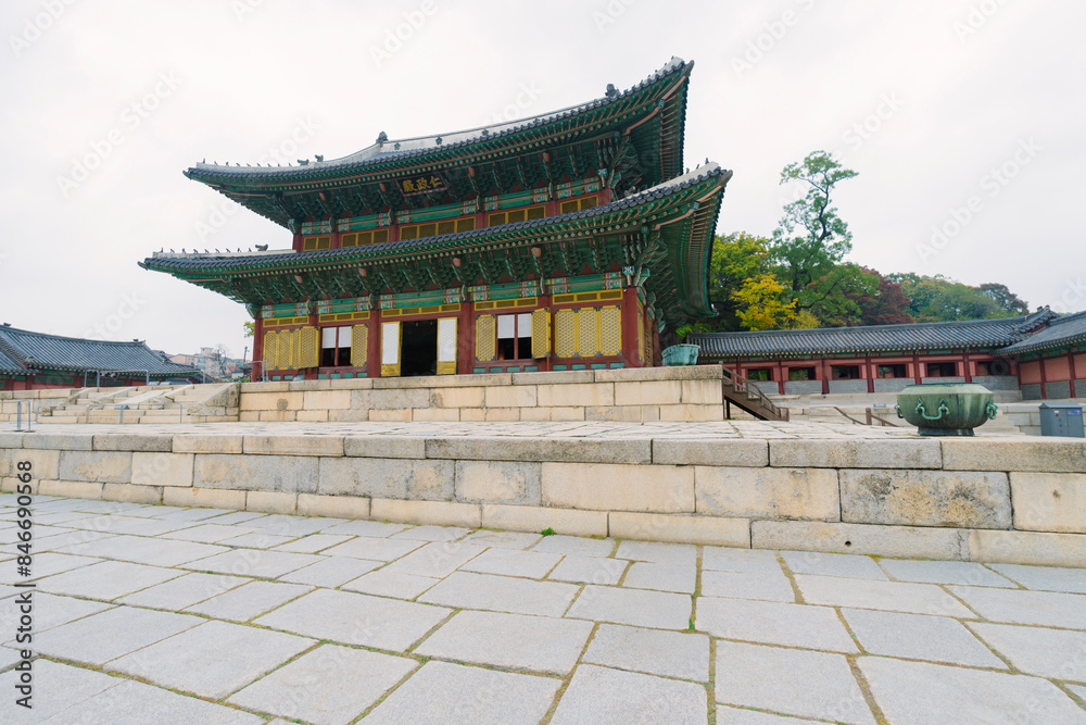 a traditional Korean palace at Changdeokgung, showcasing ornate, multi-tiered roofing and vibrant colors, surrounded by visitors and autumn foliage a traditional Korean palace at Changdeokgung, showcasing ornate, multi-tiered roofing and vibrant colors, surrounded by visitors and autumn foliage