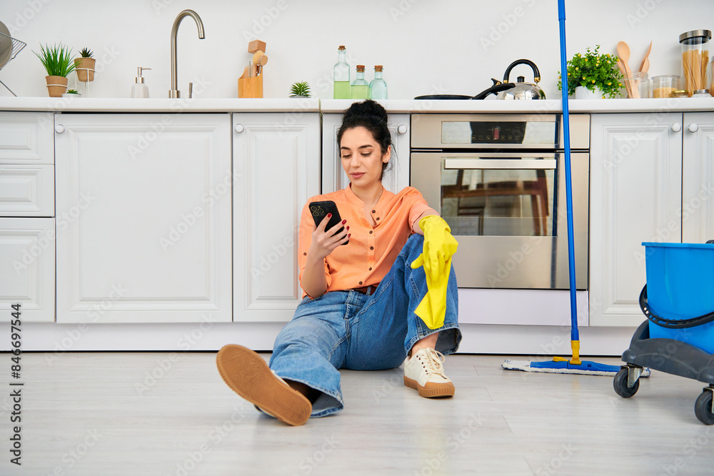 A stylish woman in casual attire sits on the floor, engrossed in her cell phone. A stylish woman in casual attire sits on the floor, engrossed in her cell phone.
