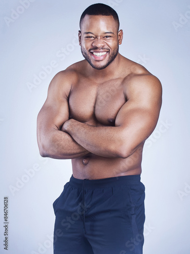 Black man, portrait and arms crossed for fitness in studio, strong muscle and shirtless on blue background. Person, confident and athlete for power or fitness, bodybuilder and topless for wellness