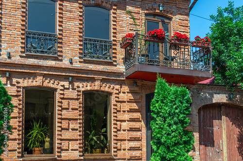 An old two-storey red brick house. The house territory is decorated with trees. The ancient architecture of the last century. The brickwork of an old house.