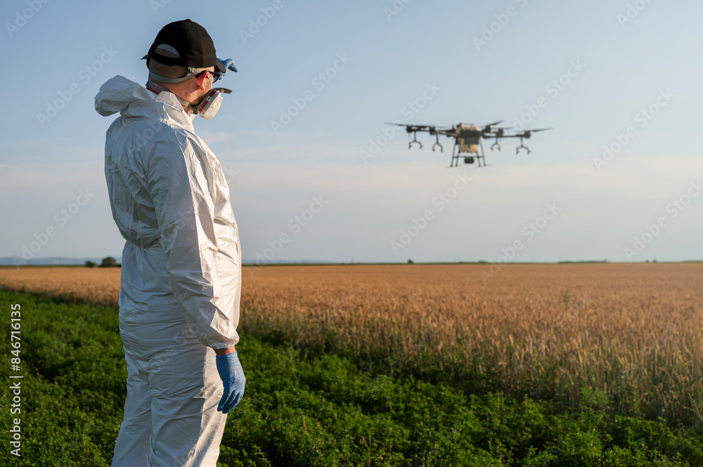 Man operates agricultural drone. Modern technologies in agriculture. Industrial drone flies over a green field and sprays pesticides to increase productivity and destroys harmful insects. Technologies