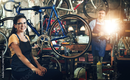 People, portrait and bicycle mechanic with teamwork for inspection, maintenance or small business at repair shop. Man, woman or cycling engineers working on bike with tools or equipment at workshop