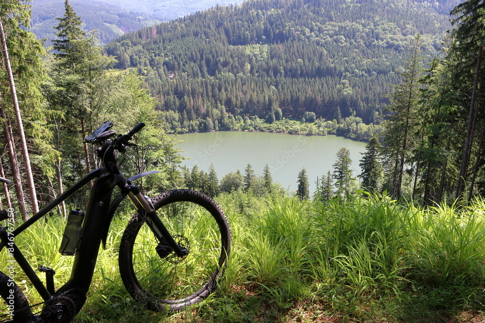 Standing e-bike with a view of the lake. In the background is the Moravka reservoir in the Czech Republic. Standing e-bike with a view of the lake. In the background is the Moravka reservoir in the Czech Republic.