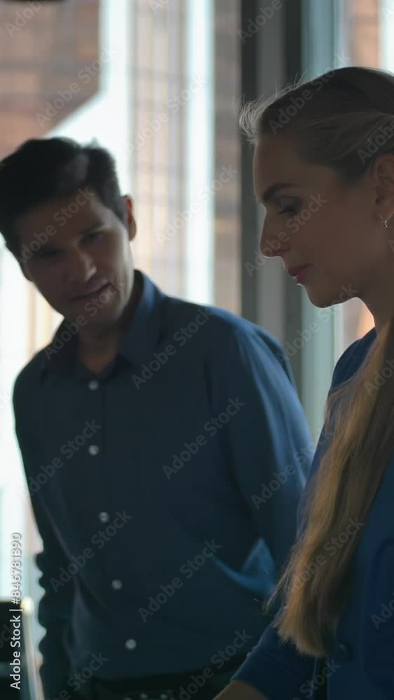 Business people using a digital tablet in a business environment. Attractive lady and handsome entrepreneur manage mobile contacts to future business deal cooperating. Vertical shot. Business people using a digital tablet in a business environment. Attractive lady and handsome entrepreneur manage mobile contacts to future business deal cooperating. Vertical shot.