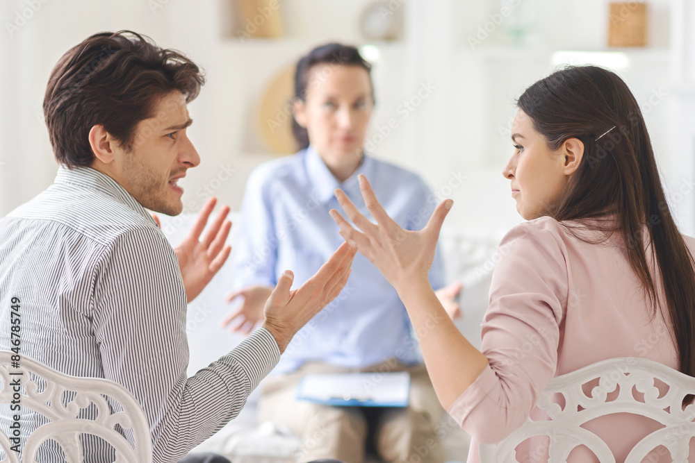 Fototapeta premium A couple is engaged in an intense discussion while their therapist observes in a bright, modern office setting during the morning.