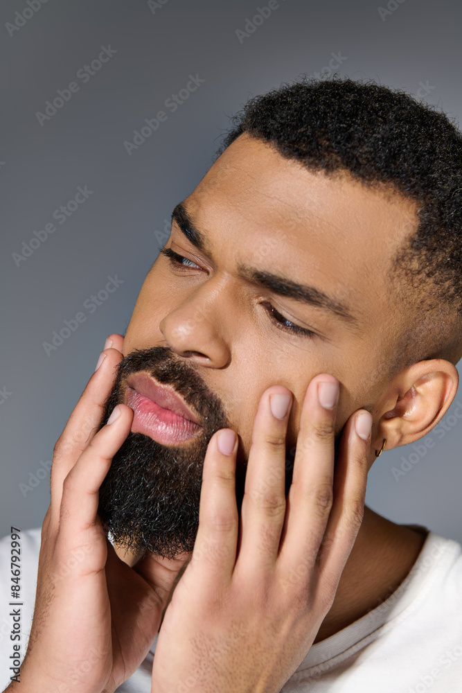 Handsome young man in white t-shirt tending to his beard. Handsome young man in white t-shirt tending to his beard.
