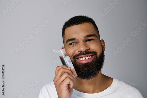 African american appealing man with a beard applying locion on his face.