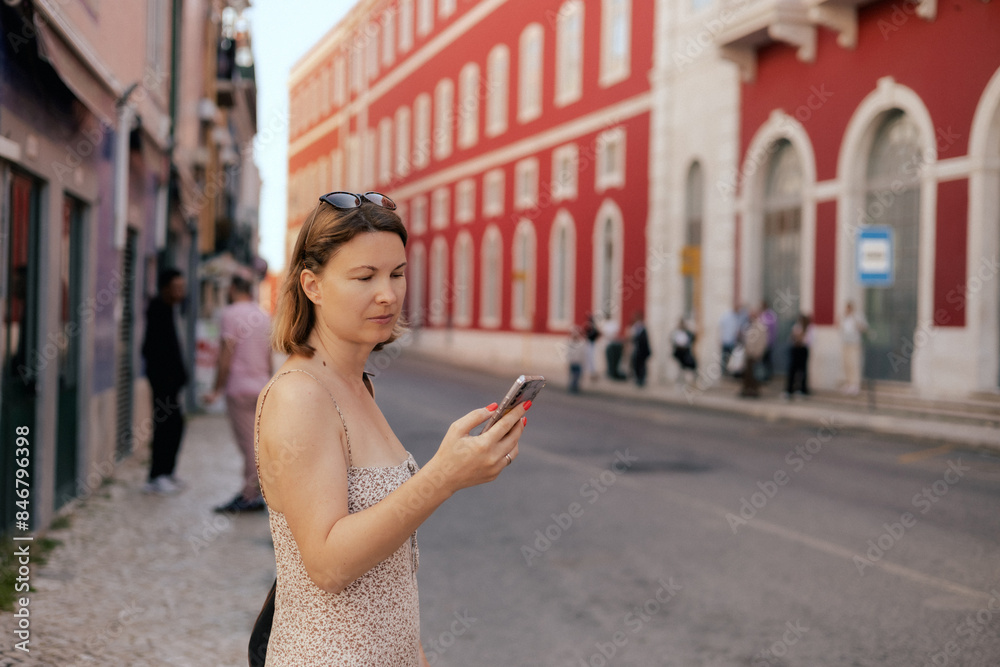 City travel concept. Tourist Woman looking at a ticket on her phone and waiting for transport at station, passenger books a ticket online through in the application. Copy space. Part of the series City travel concept. Tourist Woman looking at a ticket on her phone and waiting for transport at station, passenger books a ticket online through in the application. Copy space. Part of the series