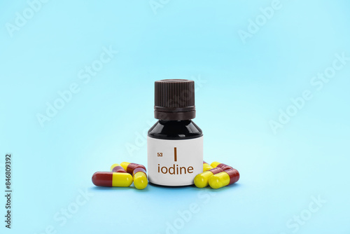 Bottle and iodine pills on light blue background photo