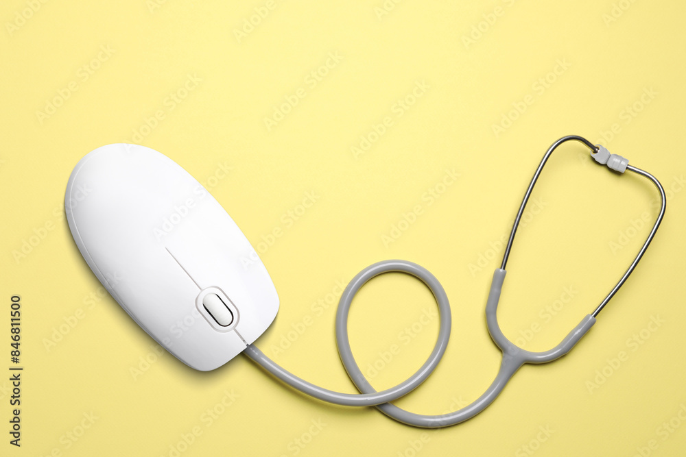 Computer mouse with stethoscope on pale yellow background, top view. Online medicine Computer mouse with stethoscope on pale yellow background, top view. Online medicine