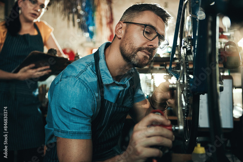 Fixing bicycle, mechanic and man with woman for startup, garage tools and clipboard for service checklist. Mentor guy, bike inspection and girl with notes for technician internship in repair workshop © peopleimages.com