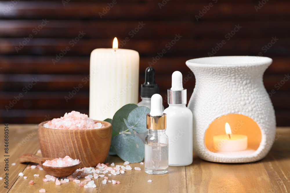 Different aromatherapy products, burning candles and eucalyptus leaves on wooden table Different aromatherapy products, burning candles and eucalyptus leaves on wooden table