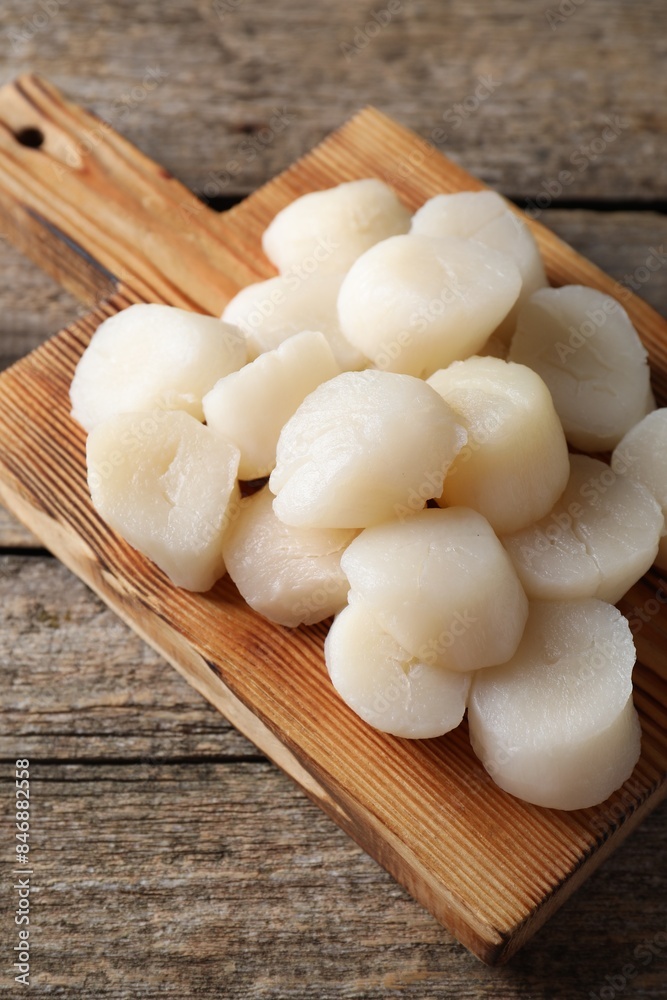 Board with fresh raw scallops on wooden table Board with fresh raw scallops on wooden table