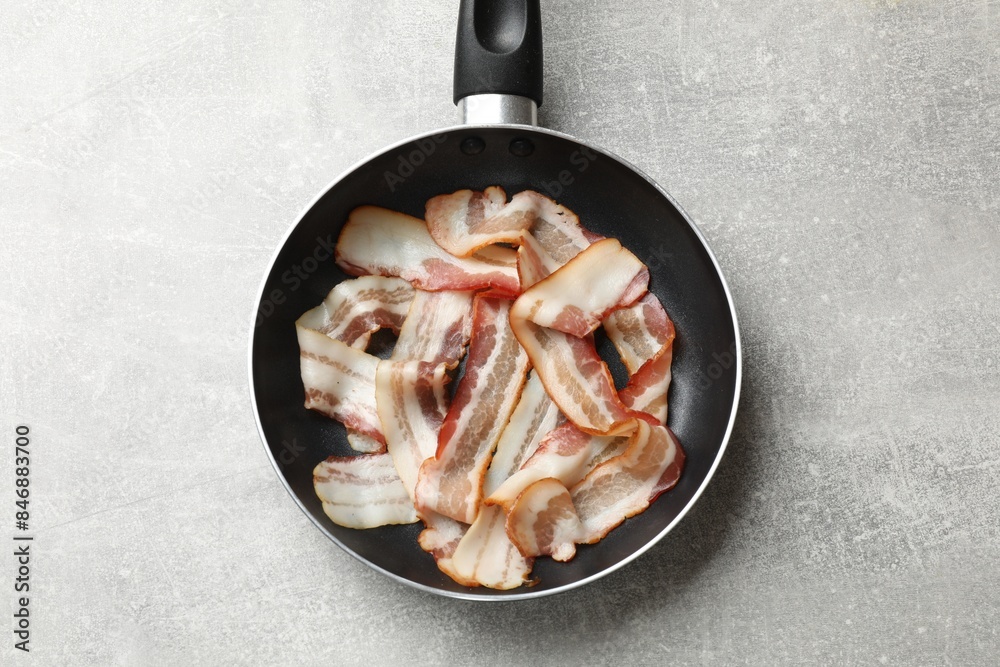 Delicious bacon slices in frying pan on light grey table, top view Delicious bacon slices in frying pan on light grey table, top view