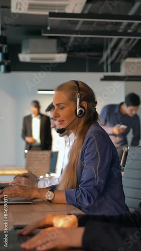 Female operator agent with headsets working in a call centre. They speaking about transaction and purchasing corporate plan of their big company. 4K UltraHD refocusing between people. Vertical shot. photo