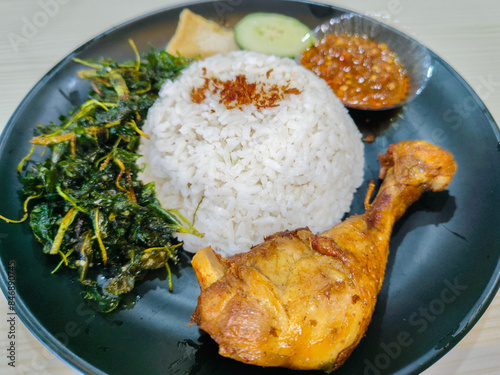 lalapan or ayam ganja or Fried chicken thighs with rice and fried cassava leaves photo