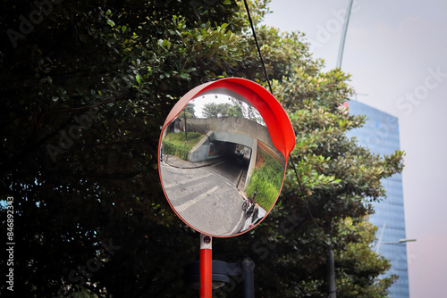 Vibrant orange convex mirror installed at intersections or bends for safety and visibility photo