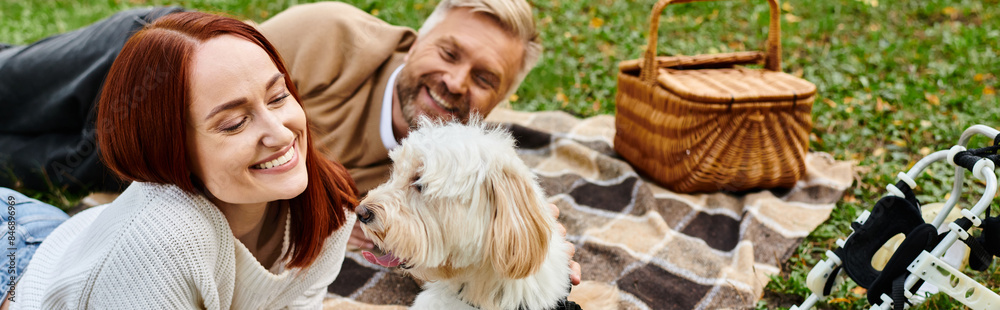 A man and woman relax on a cozy blanket with their dog in a park. A man and woman relax on a cozy blanket with their dog in a park.