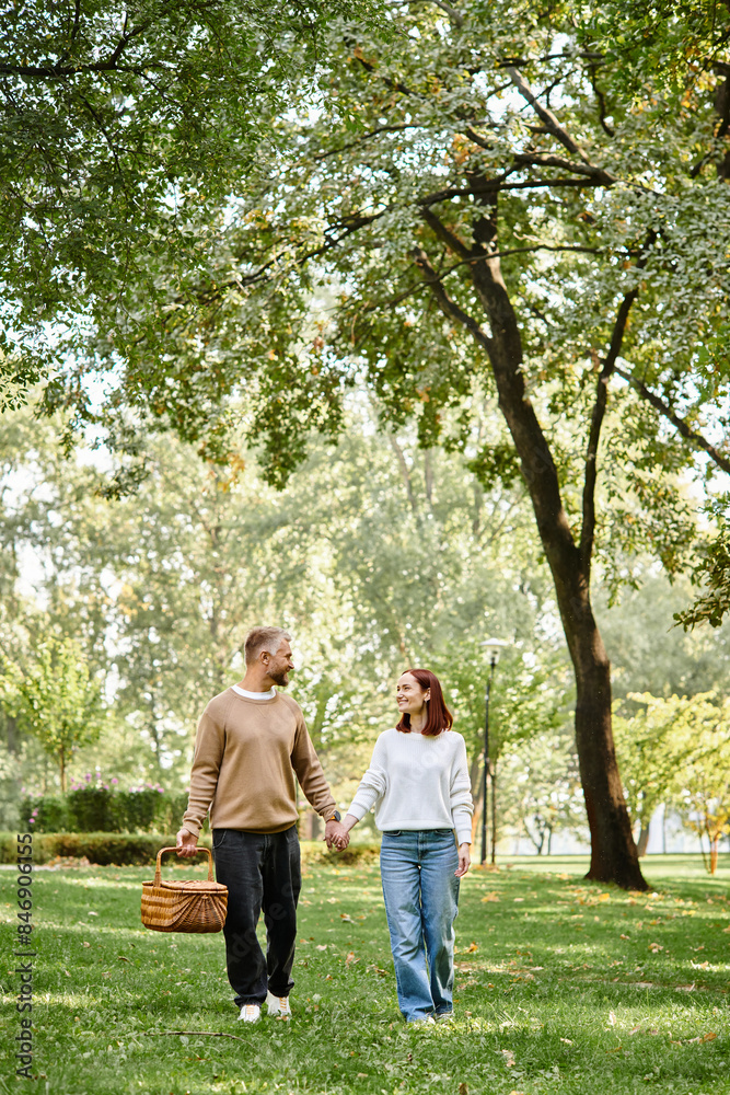 Man and woman in casual attire holding hands, walking through park. Man and woman in casual attire holding hands, walking through park.