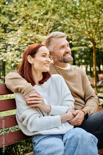 A man and woman enjoy a peaceful moment on a bench in the park.