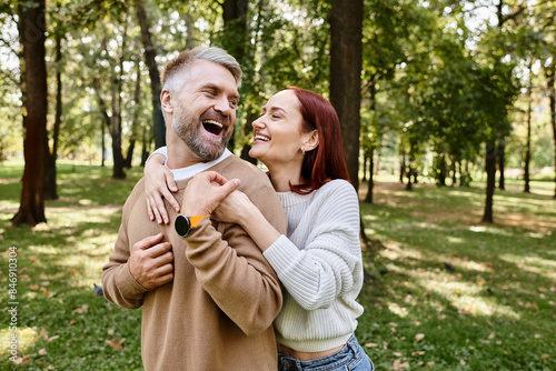 A man tenderly holds a woman in a park setting. © LIGHTFIELD STUDIOS