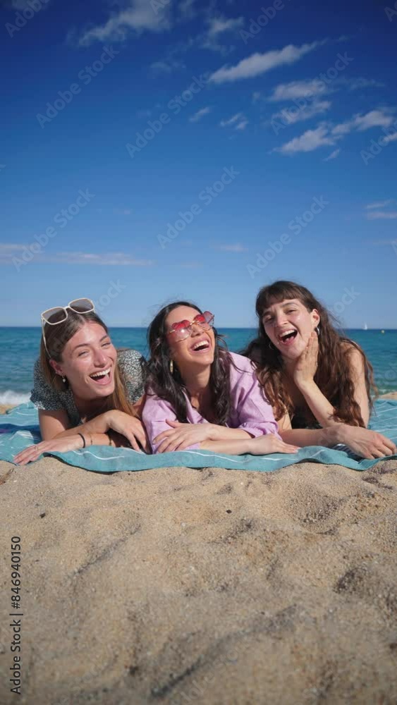 Vertical. Group of only women lying down on the sand of the beach, smiling and looking at camera. Three young female friends laughing together on the seacoast on a sunny weekend day. Girls enjoying Vertical. Group of only women lying down on the sand of the beach, smiling and looking at camera. Three young female friends laughing together on the seacoast on a sunny weekend day. Girls enjoying