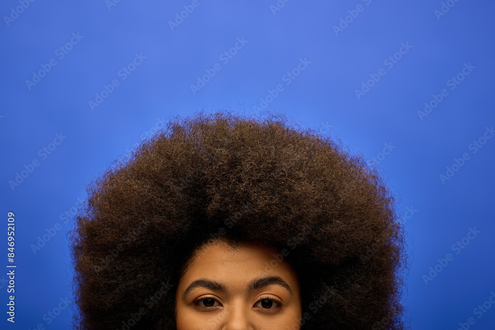 Stylish African American woman with curly hairdoon vibrant blue backdrop. Stylish African American woman with curly hairdoon vibrant blue backdrop.