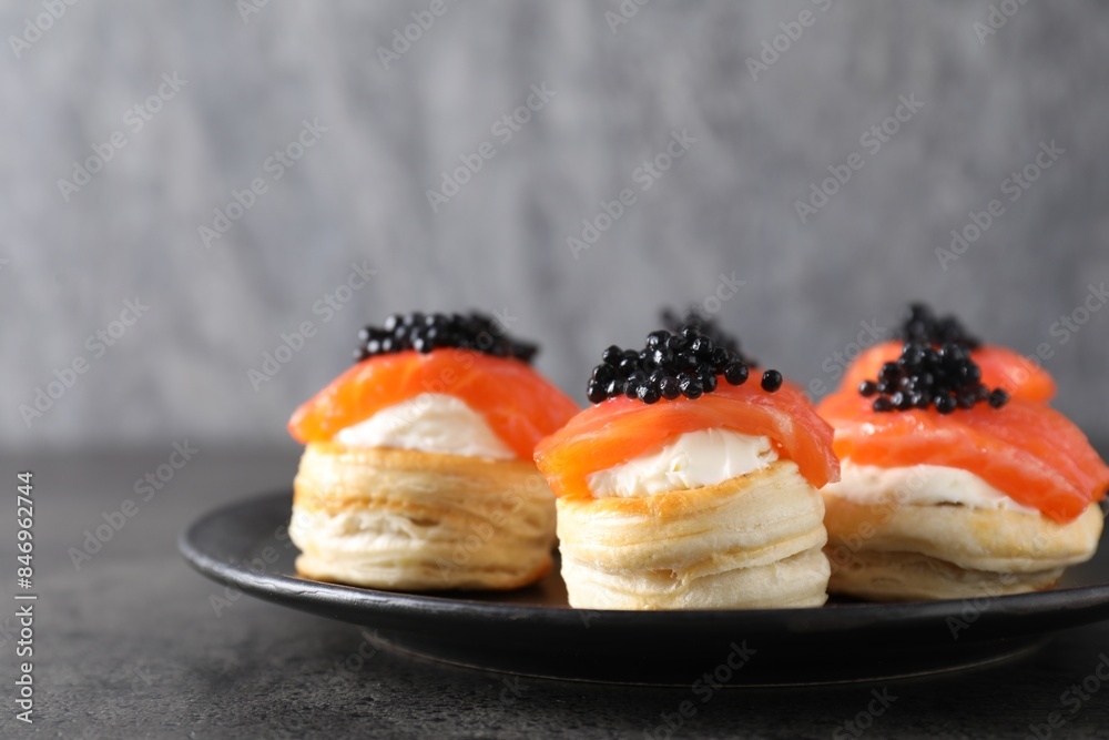 Delicious puff pastry with cream cheese, salmon and black caviar on grey table