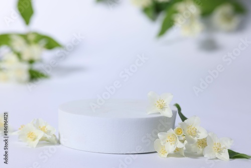 Presentation of product. Podium and beautiful jasmine flowers on white background