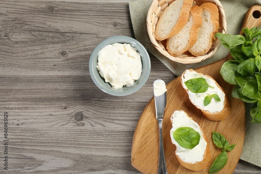 Delicious sandwiches with cream cheese and basil leaves on wooden table, flat lay. Space for text Delicious sandwiches with cream cheese and basil leaves on wooden table, flat lay. Space for text