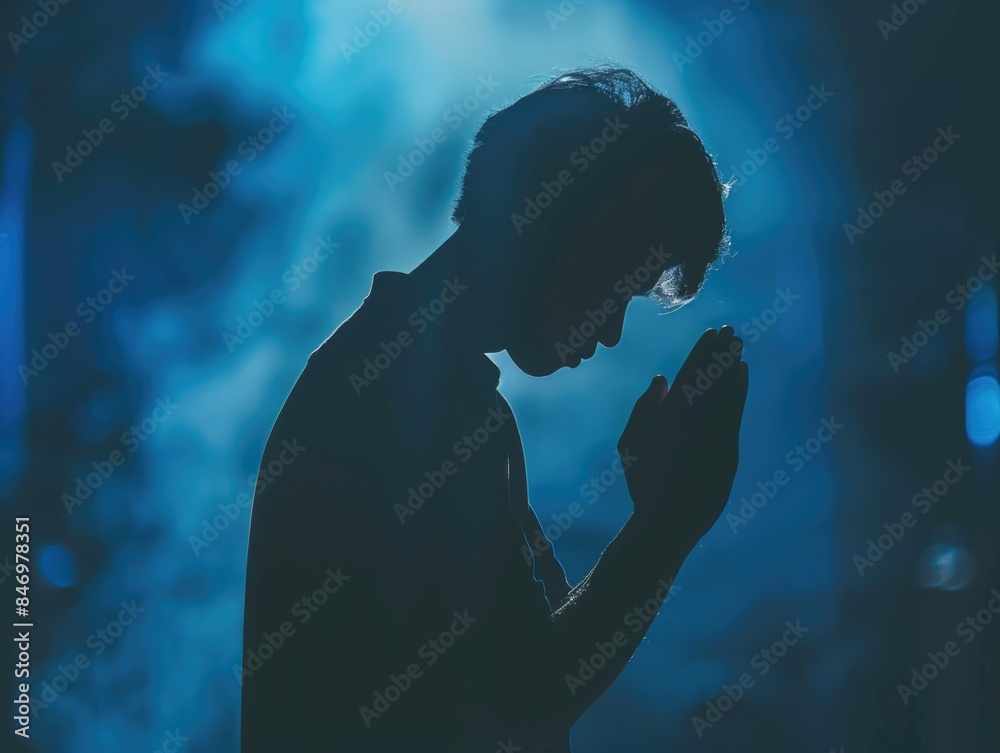 A person is shown kneeling and praying in a dimly lit room, highlighting the importance of faith and spirituality A person is shown kneeling and praying in a dimly lit room, highlighting the importance of faith and spirituality