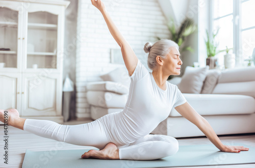 Elderly Caucasian woman practicing yoga at home in white outfit. She appears focused and serene Free Download Elderly Caucasian woman practicing yoga at home in white outfit. She appears focused and serene - GFXLoad