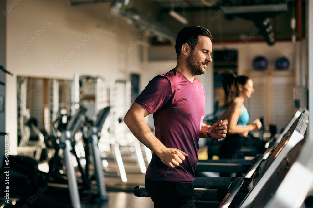 The male and his female partner running on a treadmill at the gym. The male and his female partner running on a treadmill at the gym.