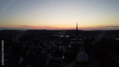 Drohnenaufnahme von hohem Kirchturm von Diedorf bei Sonnenuntergang