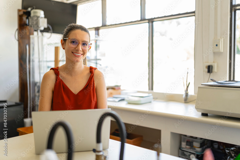 Happy scientist smiling and sitting at the table with a laptop Happy scientist smiling and sitting at the table with a laptop