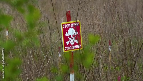 A warning sign with the inscription Stop mines in the middle of a field with thick grass. Mine safety. The concept of humanitarian demining. photo