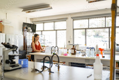 Focused microbiologist working with laptop in modern laboratory photo